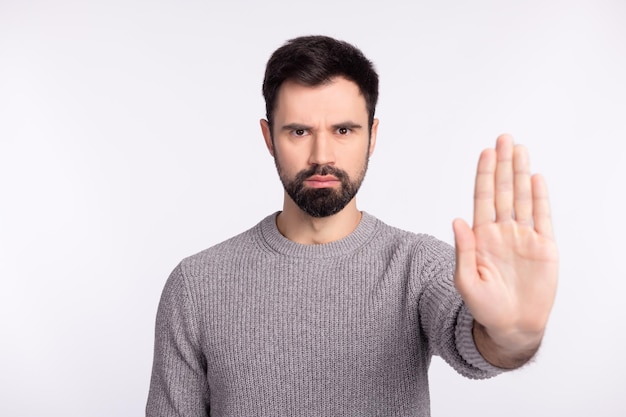 Foto van jonge man sho hand geen stop weigeren afwijzing symbool vermijd blok geïsoleerd over grijze kleur achtergrond