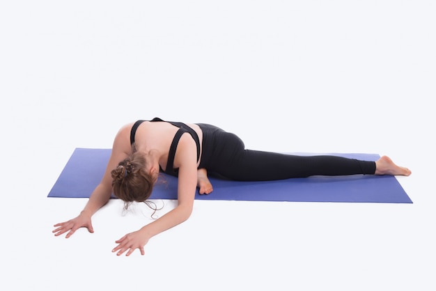 Foto van jonge sportvrouw die yoga op mat over witte ruimte in studio doet