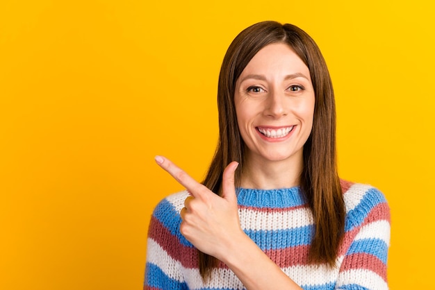 Foto van jonge vrouw gekleed shirt glimlachend wijzende vinger lege ruimte advertenties promo geïsoleerd op gele kleur achtergrond