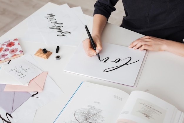 Foto van jonge vrouw handen schrijven mooie notities op papier met open boek op bureau geïsoleerd