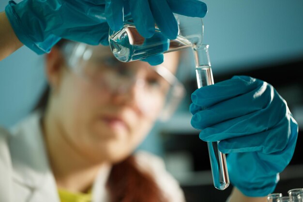 Foto van laboratoriumassistent die chemische tests uitvoert met buisjes aan tafel