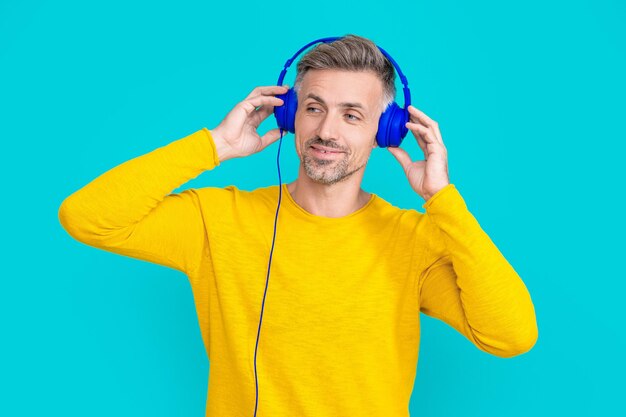 Foto van lachende man luisteren muziek in koptelefoon man luisteren muziek in koptelefoon geïsoleerd op blauw