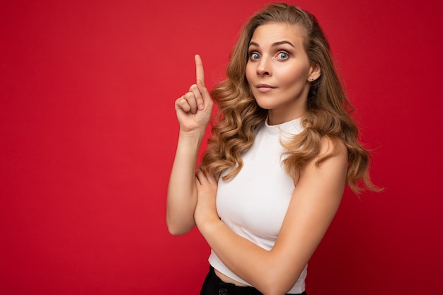 Foto van leuke leuke innemende positieve volwassen vrouw, gekleed in casual outfit geïsoleerd op de achtergrondmuur met kopie ruimte wijzend op vrije ruimte met handen.