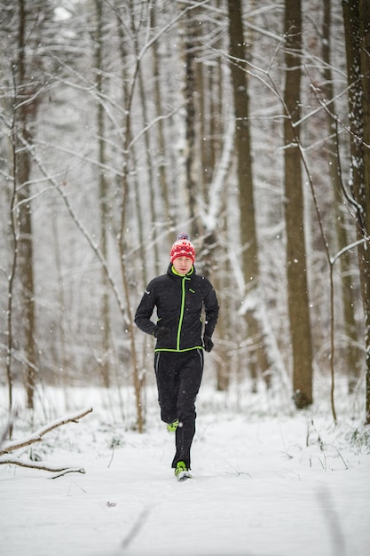 Foto van man in sportkleding rode pet op run in de winter