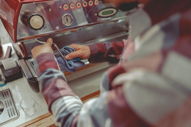 Foto van mannelijke handen van barista die stoompijp afveegt