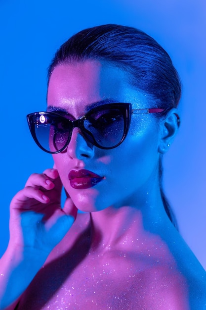 Foto van modieuze vrouw in glazen iriserende achtergrond partij disco stijl naakte schouders