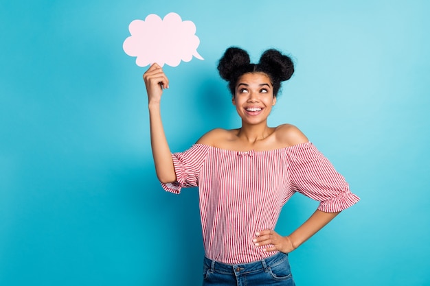 Foto van mooie donkere huid dame houden leeg papier wolk opzoeken dromerig nadenken over creatieve toespraak slijtage gestreept rood wit off-schouders blouse jeans geïsoleerde blauwe kleur muur