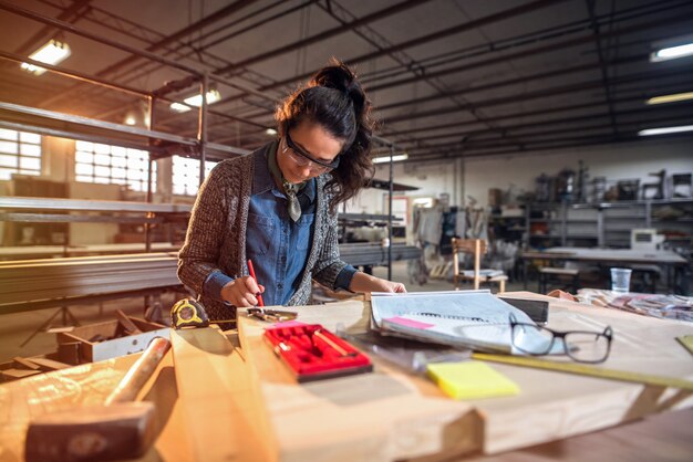 Foto van mooie gefocuste vrouw van middelbare leeftijd architect in haar atelier werken aan nieuwe projecten.