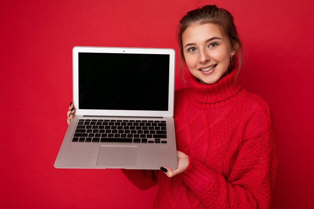 Foto van mooie jonge de computerlaptop die van de vrouwenholding camera bekijkt die over kleurrijke achtergrond wordt geïsoleerd.