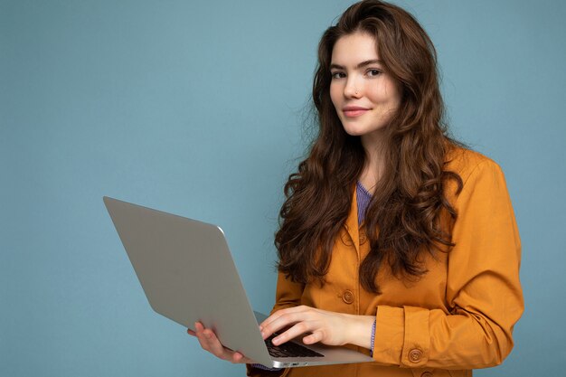 Foto van mooie jonge de computerlaptop van de vrouwenholding die camera bekijkt