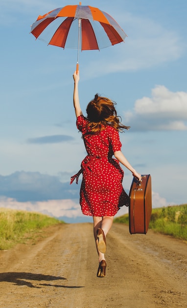 Foto van mooie jonge vrouw met koffer op de weg dichtbij gebied