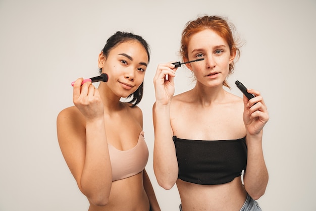 Foto van natuurlijke multiraciale vrouwen, draag ondergoed en doe make-up.