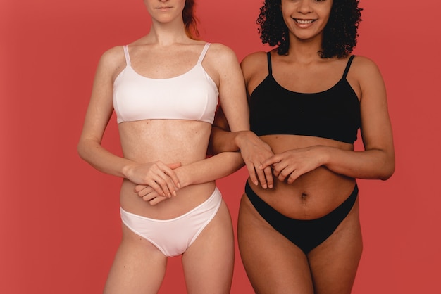 Foto van natuurlijke multiraciale vrouwen, lichaamspositief. Feministische vrouwtjes, geïsoleerd op roze achtergrond. Concept natuurlijke schoonheid en girlpower.