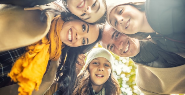 Foto van onderen op een gelukkig gezin met drie lachende kinderen die de koppen bij elkaar steken.