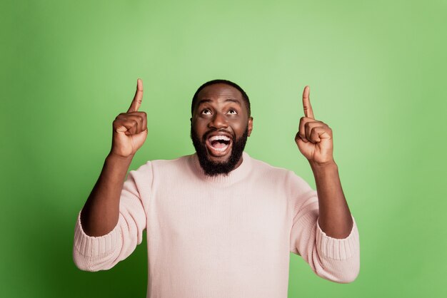 Foto van opgewonden gekke man geeft aan dat wijsvingers omhoog lege ruimte open mond dragen wit overhemd over groene achtergrond