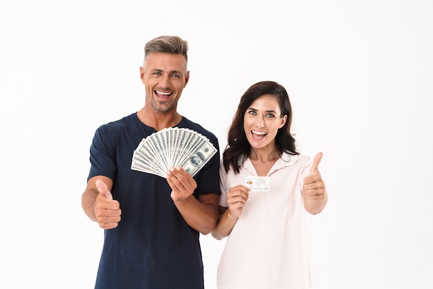 Foto foto van optimistisch volwassen verliefde paar geïsoleerd over witte muur met geld en creditcard duimen opdagen.