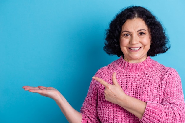 Foto van oude grappige dame directe wijsvinger optie lege ruimte draag trui geïsoleerde blauwe kleur achtergrond