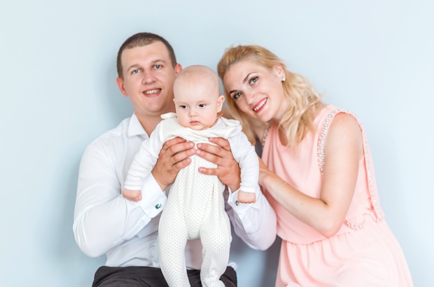 Foto van ouders met een klein kind poseren tegen de blauwe muur