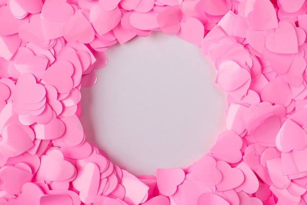 Foto van pastelroze confetti flatlay harten achtergrond met kopieerruimte in de vorm van ronde cirkelruimte in het midden