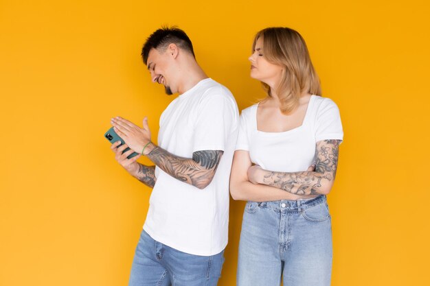 Foto van positief opgewonden mensen, man en vrouw die mobiele telefoons gebruiken, geïsoleerd over geel