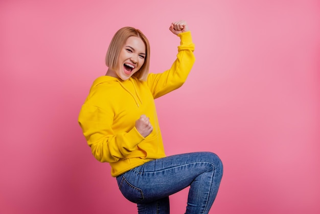 Foto van positieve kampioensdame verheug je op het behalen van het doel, draag een wit t-shirt geïsoleerd op een roze achtergrond