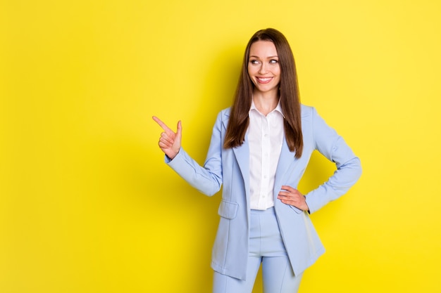 Foto van positieve zelfverzekerde bedrijfseigenaar meisje wijs wijsvinger copyspace geeft zakelijke advertenties aan promo draag stijlvolle trendy jas broek geïsoleerd over heldere glans kleur achtergrond