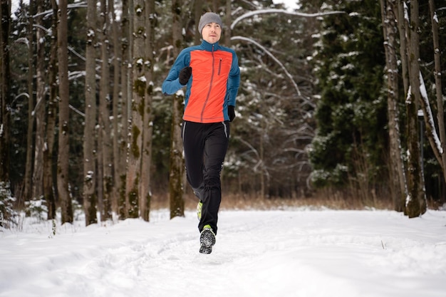 Foto van rennende atleet tussen bomen in winterbos