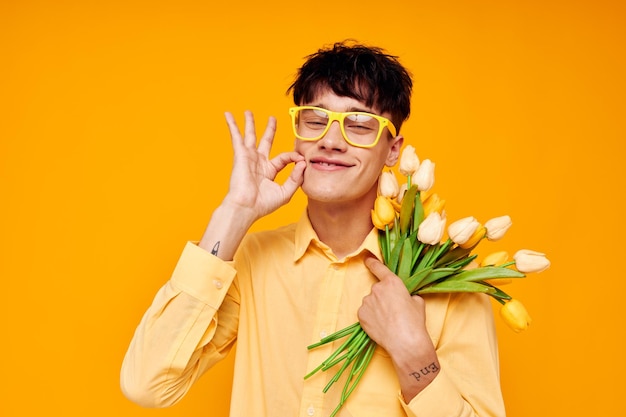 Foto van romantische jonge vriend die bloemen geeft, bril draagt geel shirt levensstijl ongewijzigd