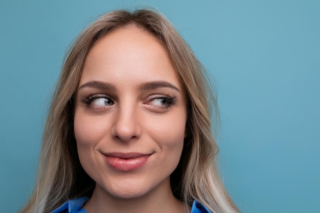 Foto van schattige casual jonge vrouw met lachende ogen op blauwe achtergrond