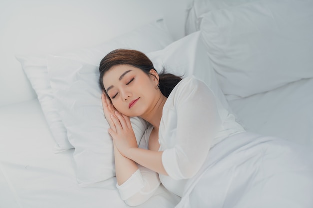 Foto van slapende jonge vrouw ligt in bed met gesloten ogen.