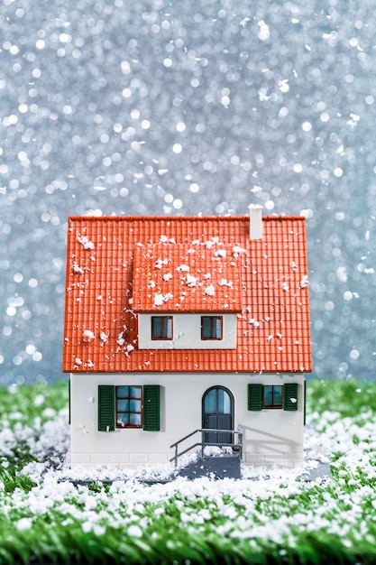 Foto van speelgoed huis met vallende sneeuw op grijze ondergrond
