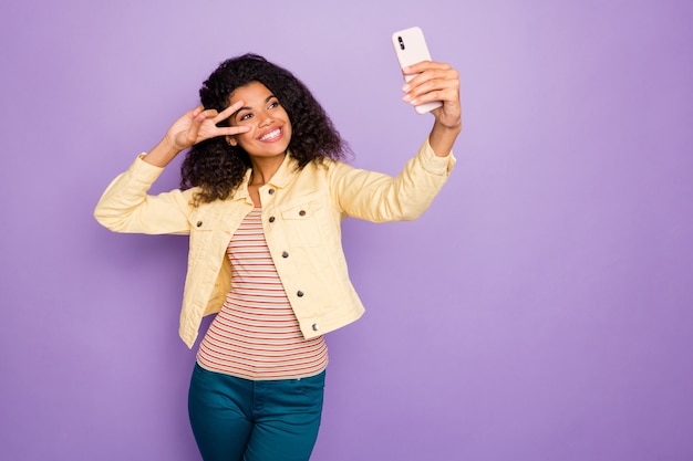 Foto van stijlvolle trendy vrolijke positieve schattig aardig meisje vsign in gestreepte t-shirt broek broek glimlach toothy geïsoleerde pastel violette kleur achtergrond tonen