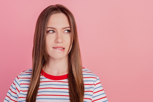 Foto van tedere meisjesachtige romantische dame die flirterige bijtlip ziet eruit als lege ruimte op roze achtergrond