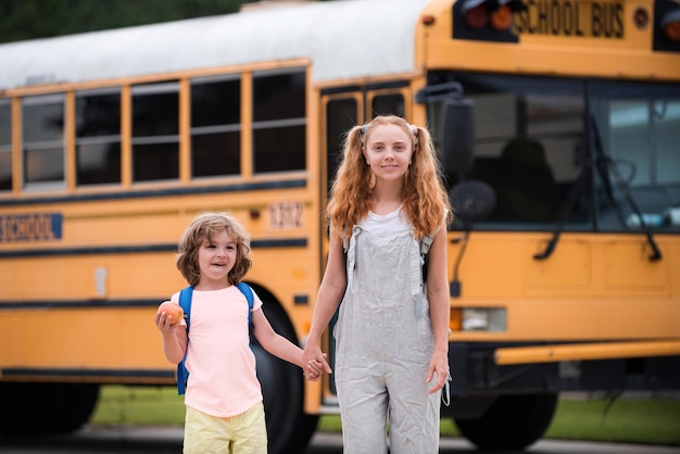 Foto van twee gelukkige kinderen die uit de ramen van een gele schoolbus kijken met veel ruimte voor tekst