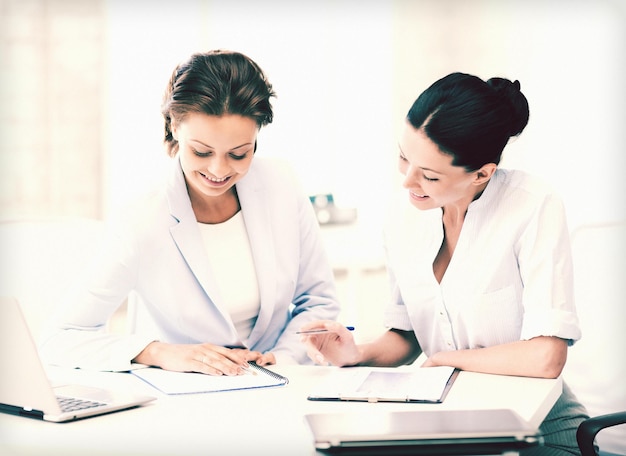 foto van twee glimlachende zakenvrouwen die op kantoor werken