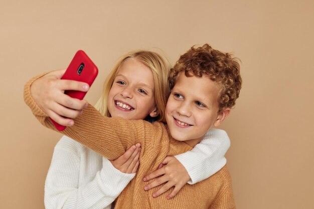 Foto van twee kinderen in truien die voor de lol poseren met een telefoon geïsoleerde achtergrond