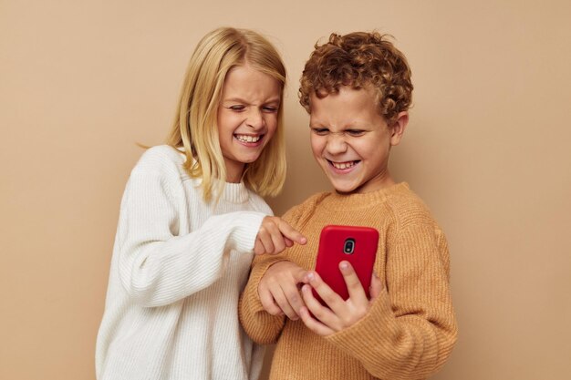 Foto van twee kinderen in truien die voor de lol poseren met een telefoon geïsoleerde achtergrond