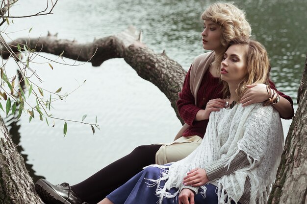 Foto foto van twee mooie vrouwen die zich voordeed op een boom in de buurt van meer.