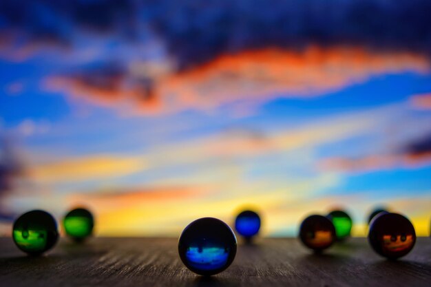 Foto van vele gekleurde glazen ballen op een houten plank op een wazige achtergrond