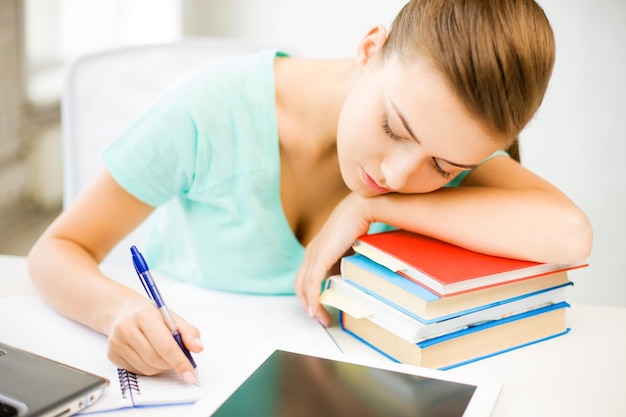 Foto van vermoeide student slapend op voorraad boeken