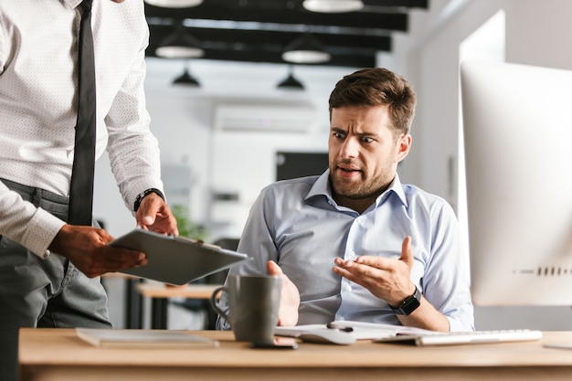 Foto van verwarde zakenman problemen op het werk zittend door de tafel in kantoor