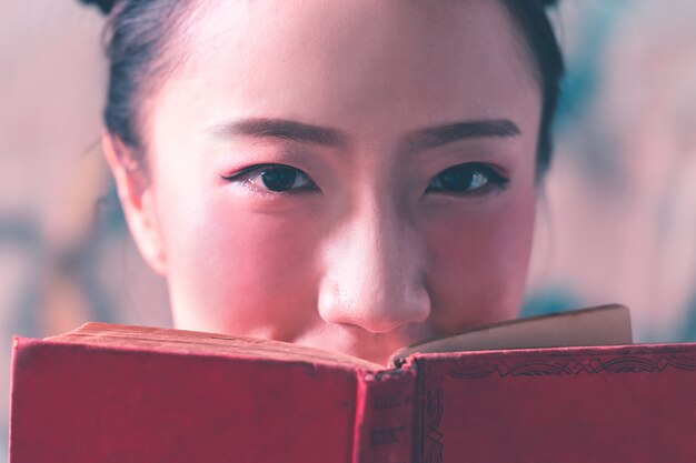 Foto van vrij Chinese dame die gezicht behandelt met rood boek.