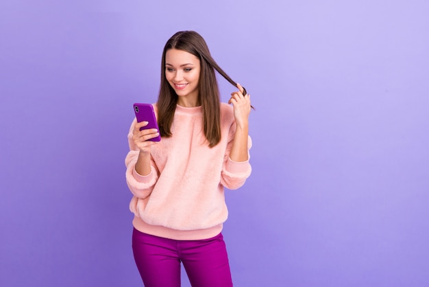 Foto van vrij verslaafde blogger dame met telefoon spelen met krul op paarse muur