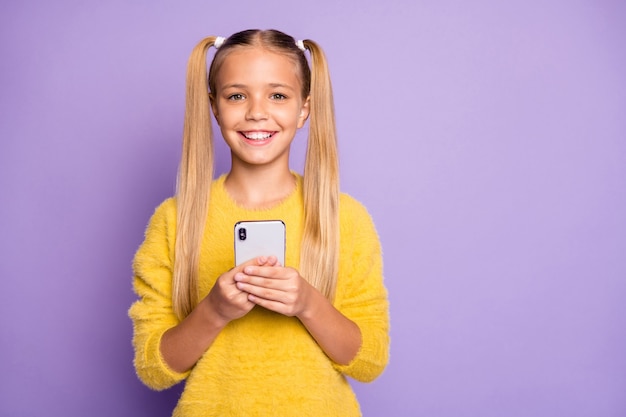 Foto van vrolijk positief leuk schattig meisje glimlachend toothily stralend in de buurt van lege ruimte geïsoleerde violette pastelkleur muur