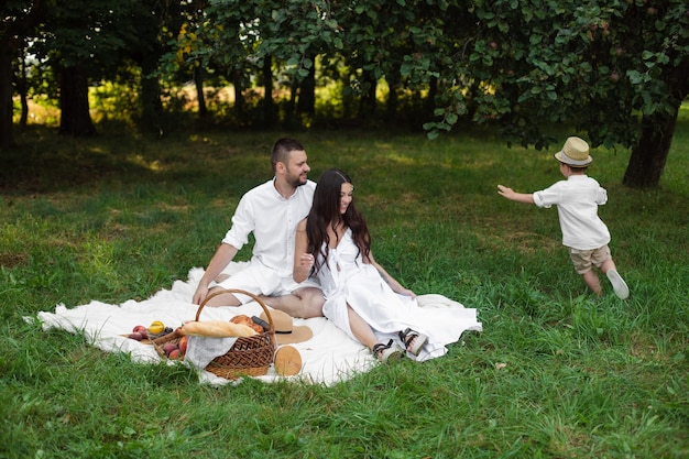 Foto van vrolijke blanke moeder, vader en hun kind hebben samen plezier en glimlachen in de tuin