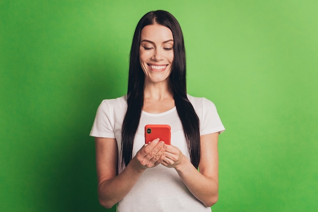 Foto van vrolijke dame met telefoon die online nieuws leest geïsoleerde groene achtergrond