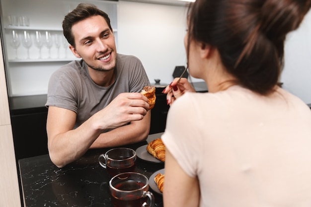 Foto van vrolijke paar man en vrouw zitten aan tafel in flat, en samen ontbijten