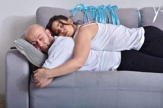 Foto van vrolijke romantische Kaukasische familie paar glimlachend en knuffelen zittend op de bank thuis. Man en vrouw verliefd