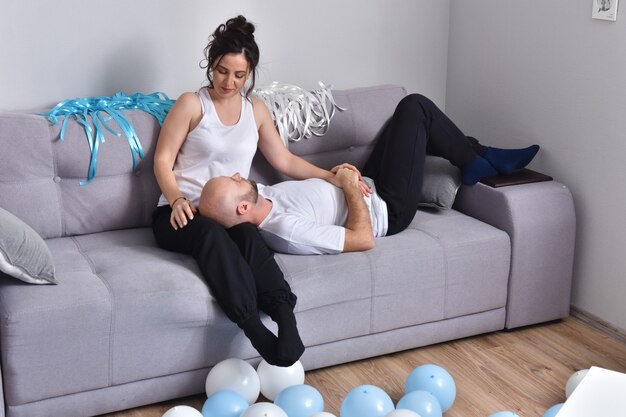 Foto van vrolijke romantische Kaukasische familie paar glimlachend en knuffelen zittend op de bank thuis. Man en vrouw verliefd