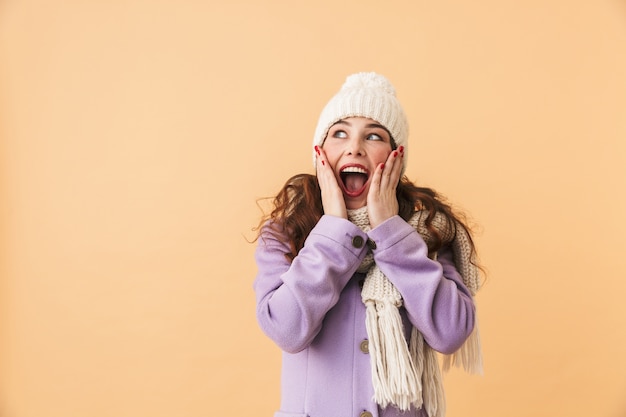 Foto van vrolijke vrouwen20s die in de winterkleren glimlachen, terwijl status geïsoleerd